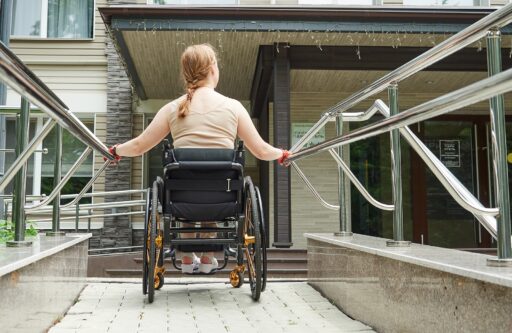 Rear view woman using a wheelchair climbs up a ramp | HOA ADA compliance