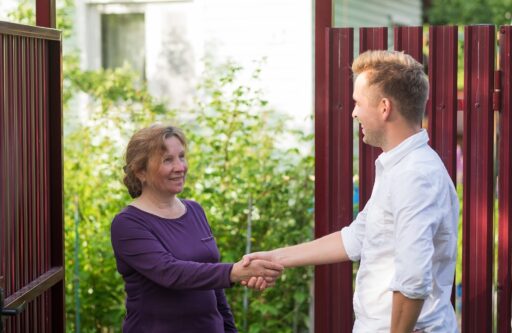 Neighbors discuss the news, standing at the fence. | HOA responsible for water damage